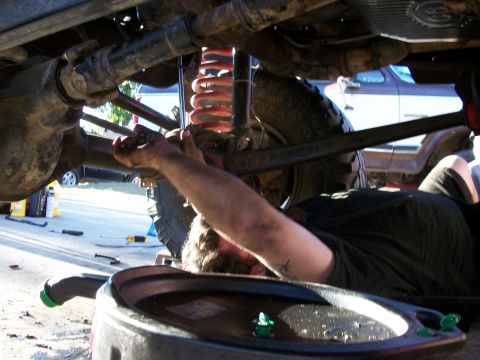 1969 Ford F-250 - A mechanic works on the suspension of a 1969 Ford F-250 during a repair day, with another vehicle visible in the background.