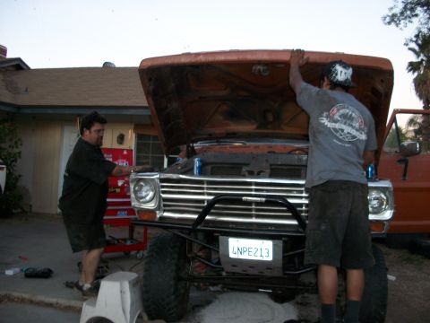 1969 Ford F-250 - Men working on the engine of a vintage Ford pickup truck in a driveway.