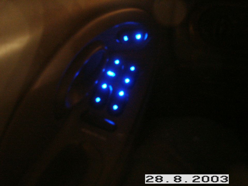 Driver's door switch panel with blue LED illuminated power window and mirror controls at night