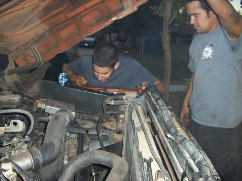 1969 Ford F-250 - Two men examine the engine of a truck with the hood open, a blue can sits on the fender.