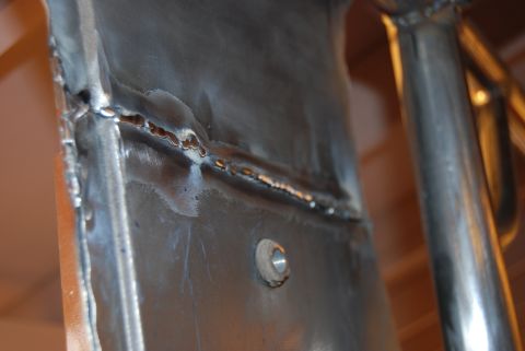 1982 Ford Bronco - Detail of a welded metal frame, showing a seam and a bolt hole. The registry claims this is a 1982 Ford Bronco, but the image shows only a…