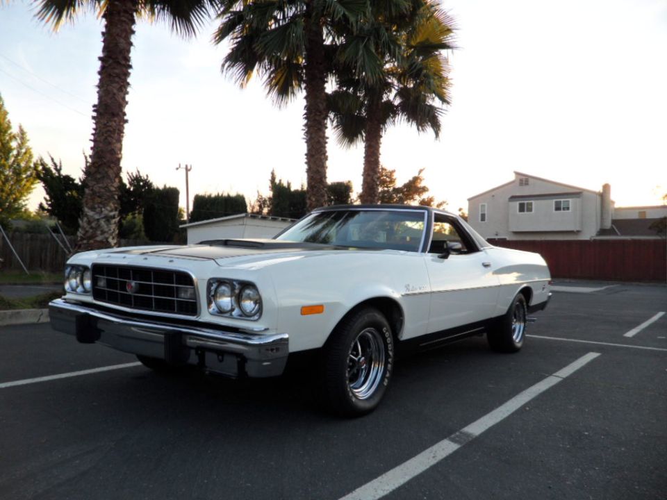 White 1972 Ford Ranchero with black hood scoop and chrome wheels parked in a lot