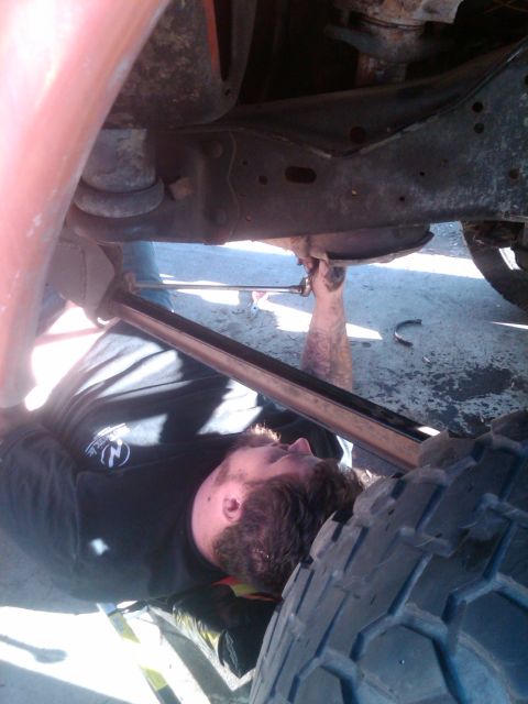 1982 Ford Bronco - A mechanic performs work underneath a vehicle, with a tire and chassis components visible in the frame.