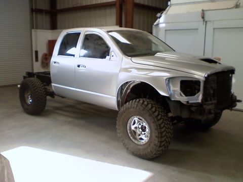 2006 Dodge 2500 - This silver pickup truck is in a garage, missing its front end components and has large off-road tires.