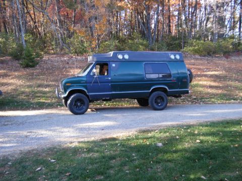1981 Ford E350 - Modified 1981 Ford E350 van with off-road tires sits on a gravel road surrounded by autumn trees.