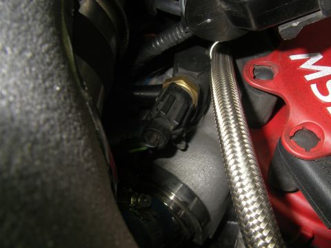 1990 Ford Bronco - Close-up view of an engine sensor and a braided hose, part of the vehicle's internal mechanics.