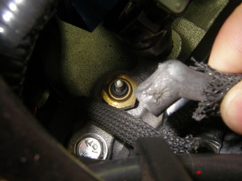 1990 Ford Bronco - A close-up view shows a brass sensor installed in an engine block, with a damaged electrical connector nearby.