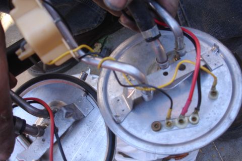 1990 Ford Taurus - A mechanic is holding a fuel pump assembly, showing its electrical connections and fuel lines.