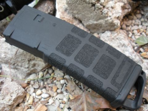 1996 Ford Bronco - A black rifle magazine with textured grip panels rests on a bed of gravel and rocks.