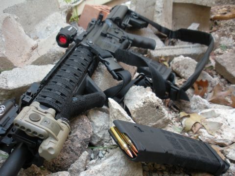 1996 Ford Bronco - Tactical rifle with accessories and magazine, placed on a pile of rocks and debris.