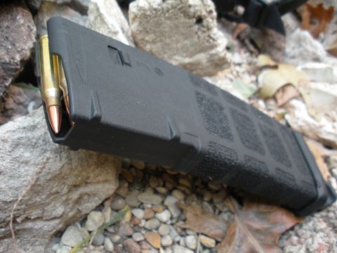 1996 Ford Bronco - Ammunition magazine loaded with cartridges, placed on a rocky surface.
