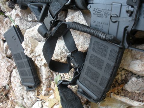 1996 Ford Bronco - A close-up view of an AR-15 rifle and its magazines resting on rocks and dirt.