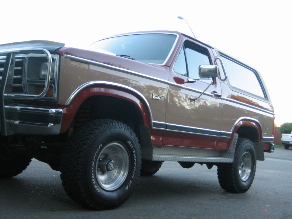 Two-tone brown and maroon Ford Bronco with chrome grille guard and aftermarket wheels