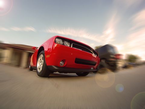 2010 Dodge Challenger - Red Dodge Challenger captured in motion, passing another vehicle on a sunny day.