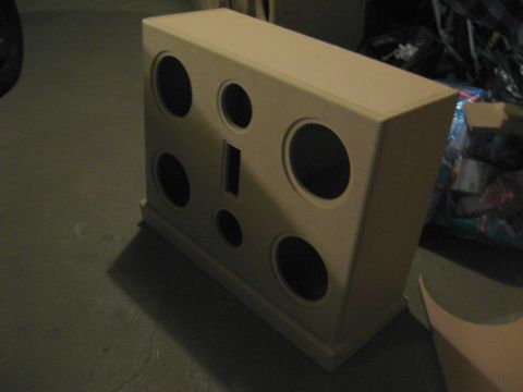 1987 Ford Bronco - A beige speaker enclosure with various sized circular openings is shown in a dimly lit room.