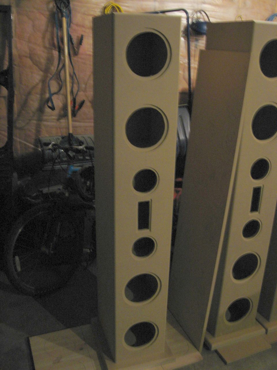 Two unfinished speaker enclosures with multiple circular and rectangular cutouts