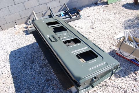 1982 Ford Bronco - A green car door is prepared for painting outdoors.