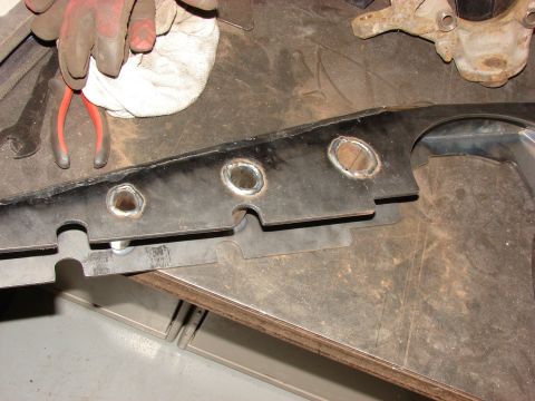 1996 Jeep Grand Cherokee - A metal bracket with circular cutouts sits on a workbench, with tools and a rusty component nearby.