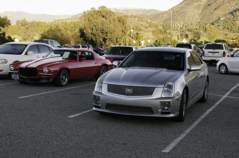 2006 Cadillac STS - A silver Cadillac STS is parked in a lot, with a classic red Camaro visible in the background.