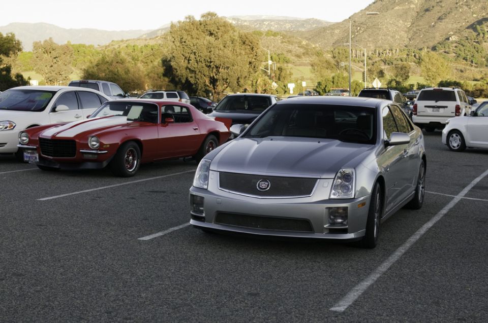 Silver 2006 Cadillac STS parked in a lot with a red Camaro behind it