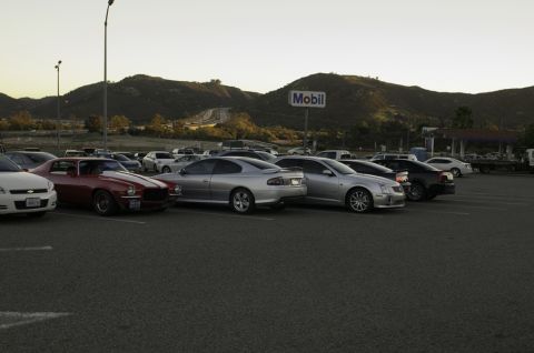2006 Cadillac STS - A variety of cars are parked in a lot with a Mobil gas station and mountains visible.