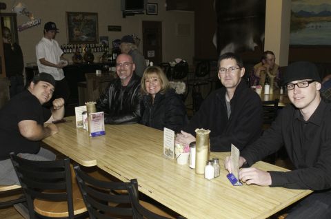 2006 Cadillac STS - Several individuals are gathered around a table inside a dimly lit establishment, possibly a bar or restaurant.