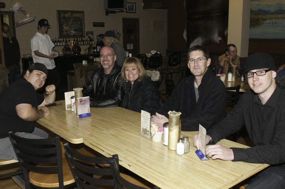 Group of people sitting at a long table in a restaurant, with a bar area in the background