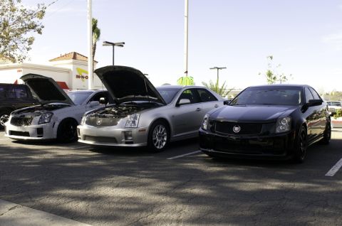 2006 Cadillac STS - Multiple Cadillac sedans are parked in a lot, with two of them having their hoods open.