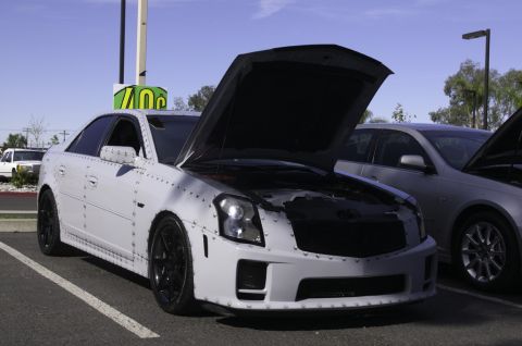 2006 Cadillac STS - This heavily modified white sedan features exposed rivets along its body panels and its hood is propped open.