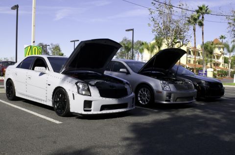 2006 Cadillac STS - Three Cadillacs, including a custom riveted white model, are parked with their hoods open.