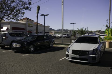 2006 Cadillac STS - Two Cadillac sedans are parked in a lot near an In-N-Out Burger, with a white one in the foreground.