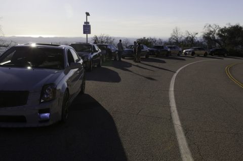 2006 Cadillac STS - A line of cars is parked on the side of a road with a scenic overlook in the background.