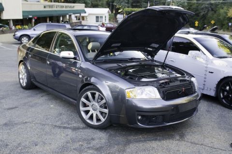 2006 Cadillac STS - This dark gray Audi sedan has its hood open, revealing the engine compartment. Another vehicle is parked alongside it.