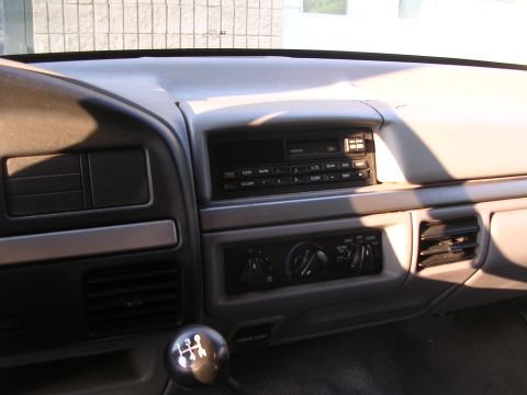 1995 Ford Bronco - The interior dashboard features a radio, climate controls, and a manual gear shift.