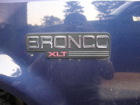 1995 Ford Bronco - Close-up of the Bronco XLT emblem on a blue vehicle's fender.