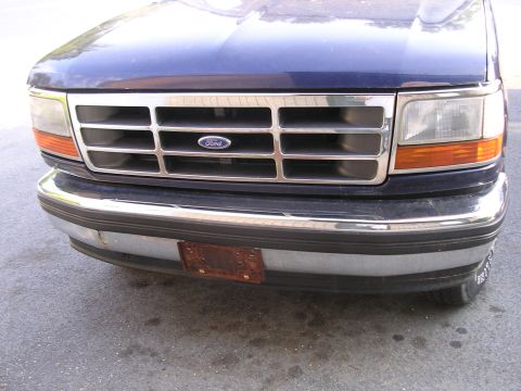 1995 Ford Bronco - Close-up of a blue Ford truck's front end, showing the grille and bumper details.