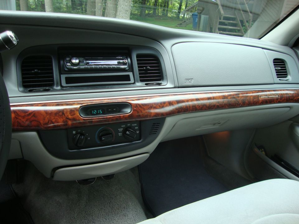 Dashboard of a 1997 Mercury Grand Marquis with wood trim, digital clock, and aftermarket stereo