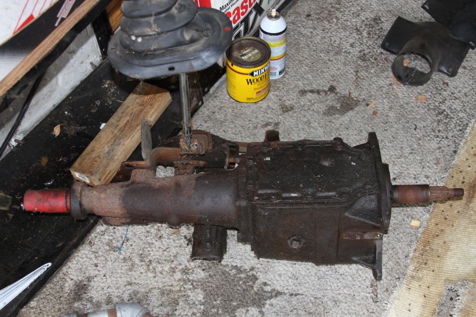 Old manual transmission with shifter boot and a can of wood stain nearby