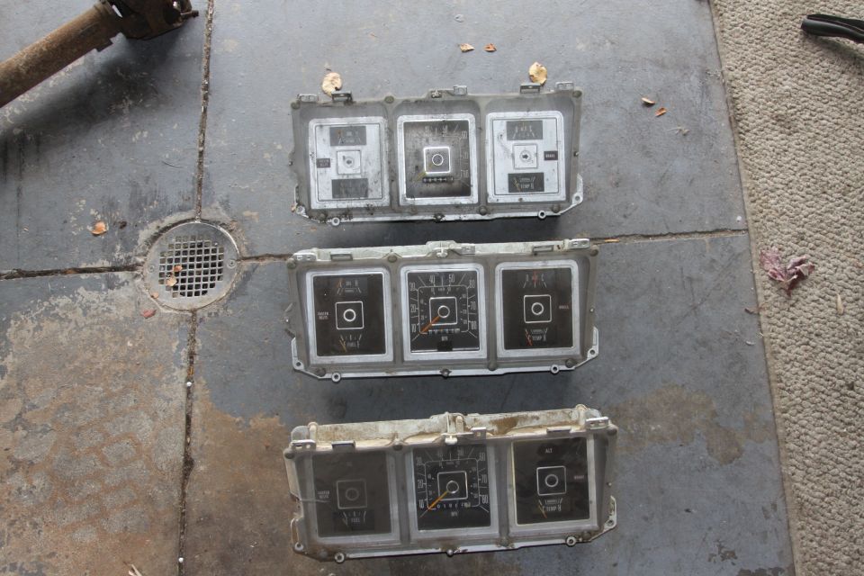 Three automotive gauge clusters on a concrete floor