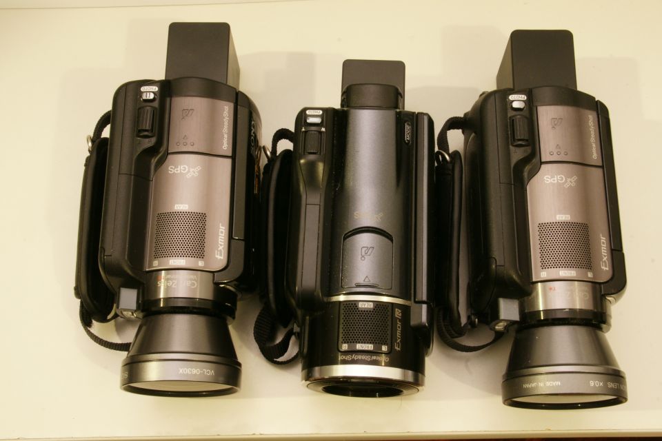 Three camcorders lined up. Two are silver and black, one is all black