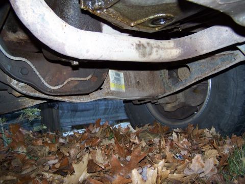 1996 Ford Bronco - A close-up view of a vehicle's undercarriage reveals suspension parts and an exhaust pipe, with a sticker visible on the frame.