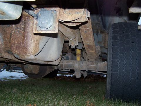1996 Ford Bronco - The rusty undercarriage of a vehicle is visible, with a fuel tank and suspension components.