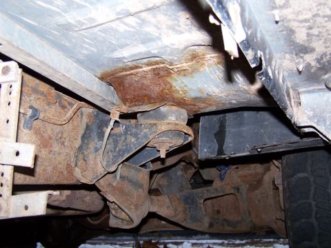 1996 Ford Bronco - Close-up view of the rusted undercarriage and suspension of a vehicle, showing signs of wear and tear.