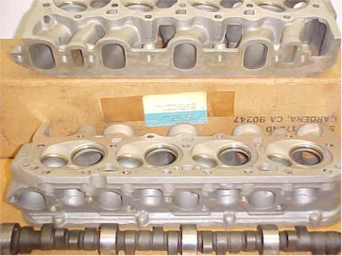 1972 Ford Ranchero - Two aluminum engine cylinder heads and a camshaft are displayed with a cardboard box and a label in the background.