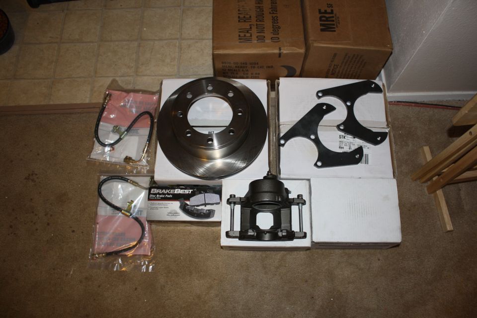 Brake rotor, caliper, brake pads, and brake lines laid out on the floor