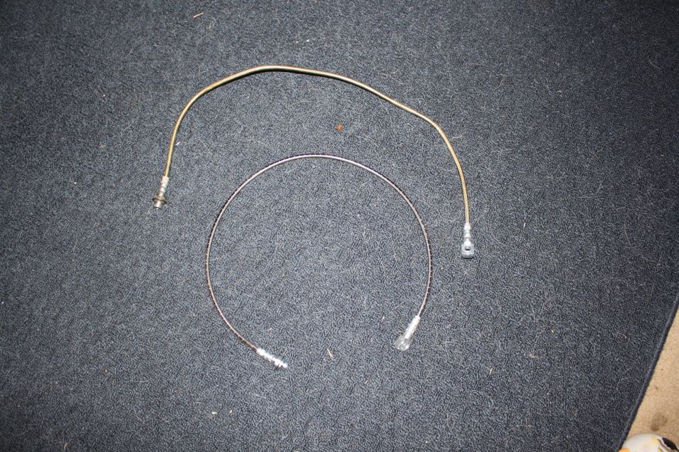 Two metal brake lines on a dark carpeted surface. One is curved, the other is a U-shape