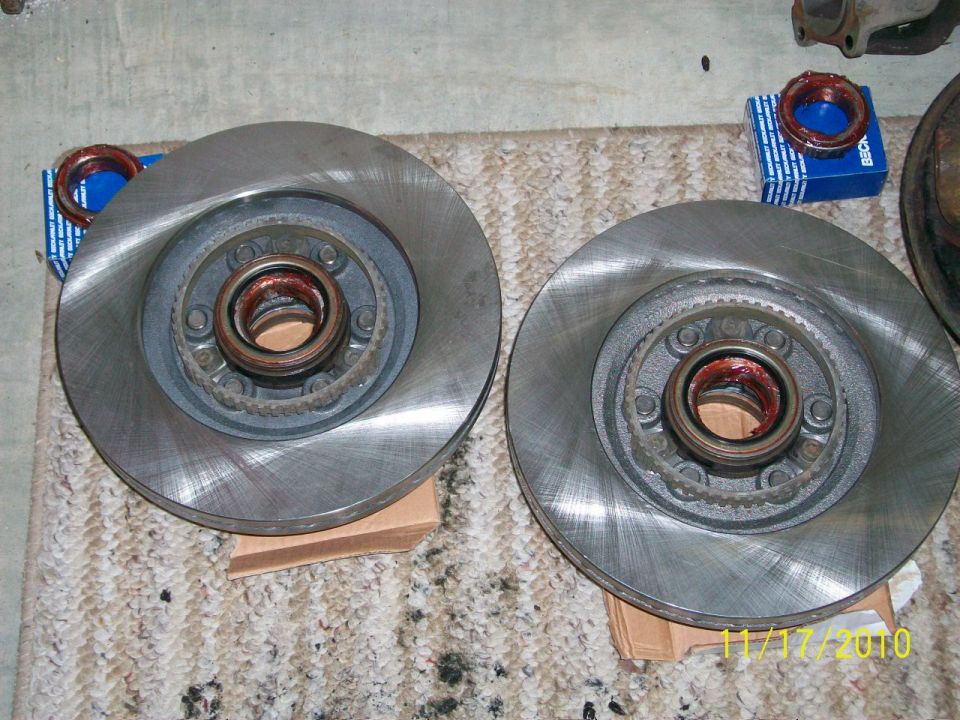 Two brake rotors with bearings and boxes of seals on a carpeted surface