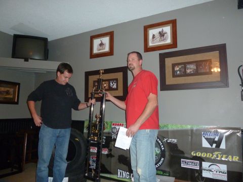 1992 Ford Mustang - Two men stand with a large trophy, possibly after a competition, with sponsor banners visible.
