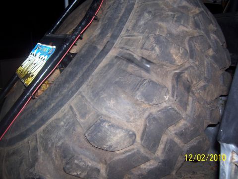 1978 Ford Bronco - A close-up view of a large, off-road spare tire and its mounting hardware, with a date stamp visible.