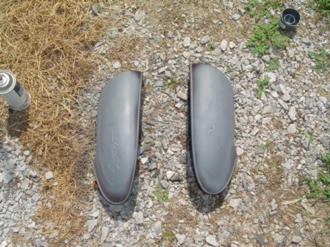 1999 Ford Taurus - Two gray car fenders are laid out on a gravel surface next to a can of spray paint.